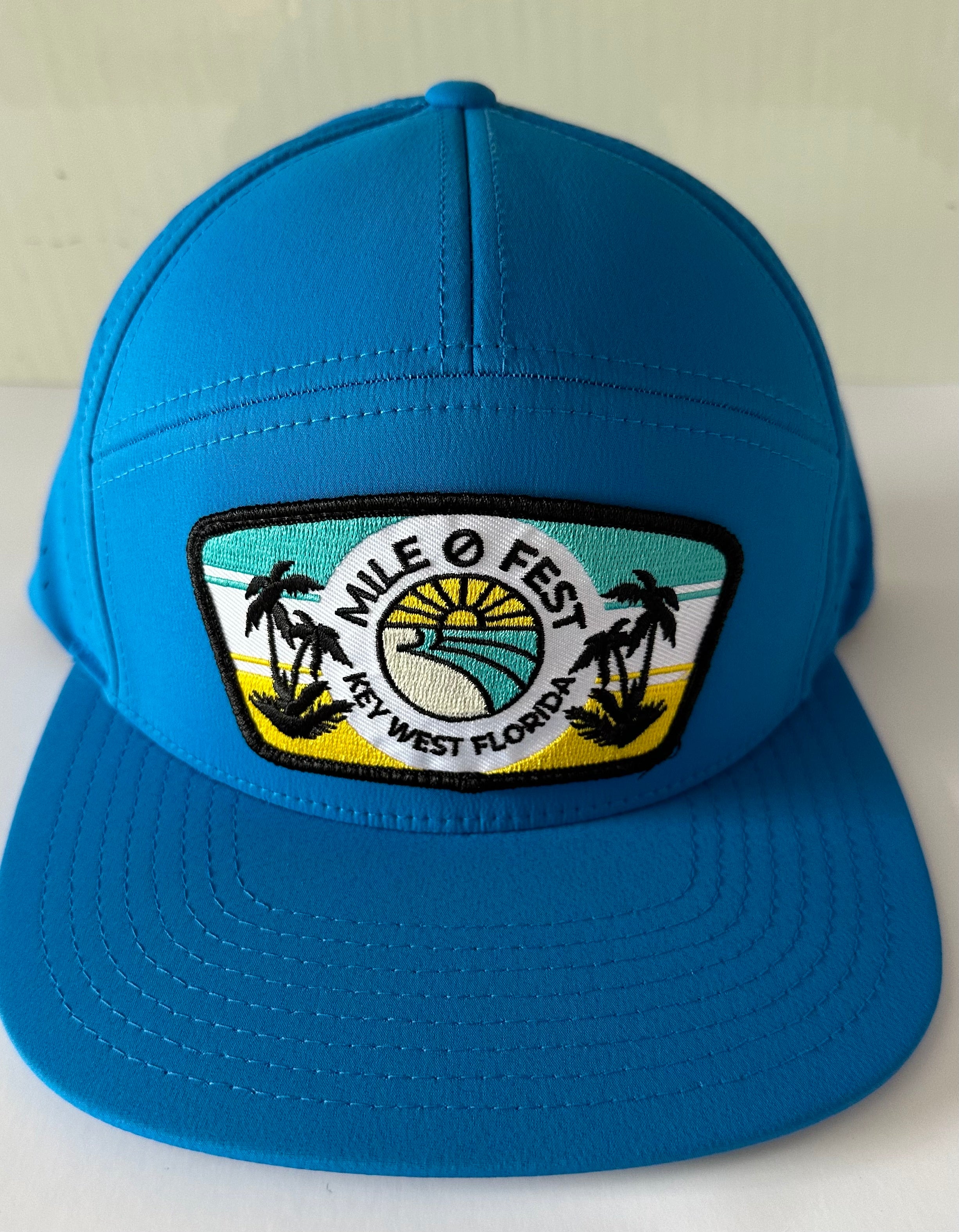 A blue baseball cap with a colorful wedge patch featuring text and palm trees.